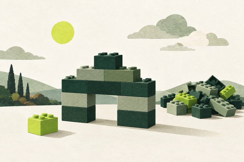 A green and sage block construction with one lime piece set aside and other unused blocks.